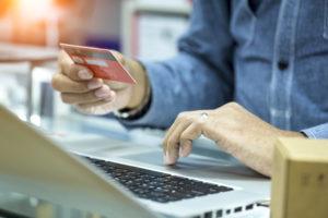 Man holding credit card and using laptop