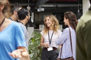 Smiling business team standing at convention center. Male and female professionals are discussing during meeting. They are wearing smart casuals.