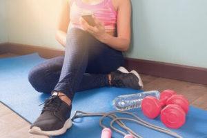 Woman working out at home on yoga mat with weights