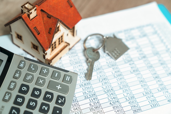 Calculator, toy house and key chain sitting on desk