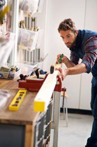 Shot of a handsome young carpenter measuring a piece of wood