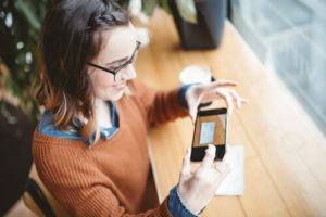 Woman taking photo of check on cell phone