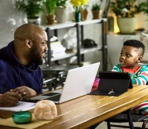 Man and son sitting on kitchen table in holiday pajamas