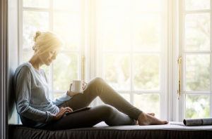 Woman drinking coffee by window