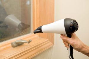 Hair dryer being used to seal plastic on windows