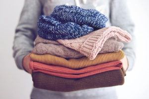Person holding pile of sweaters
