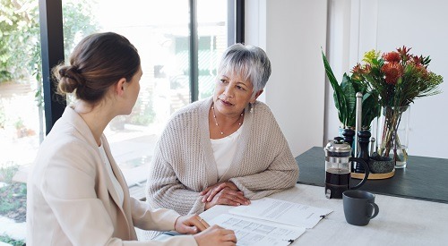 Two women speaking at table over paperwork