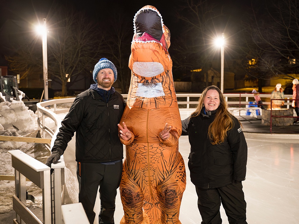 Service CU volunteers posing with a friendly dinosaur at the Family Skate Party at Puddle Dock.