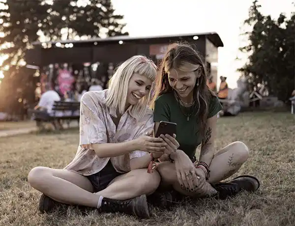 two female friends sitting outside in the grass