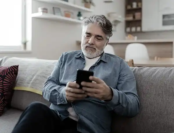 older gentleman looking at his phone on the couch
