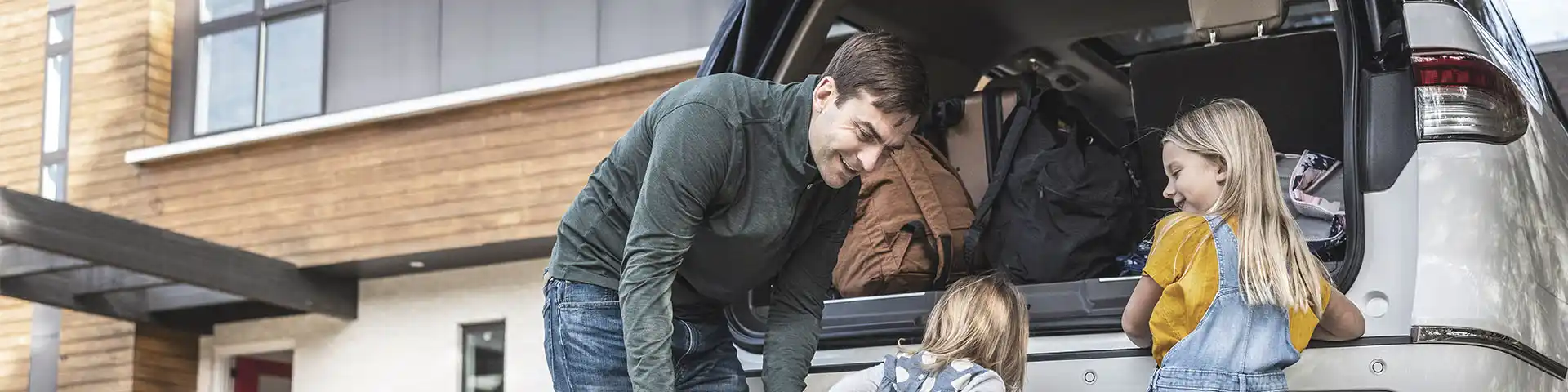 Father helping his girls load supplies in the back of the car