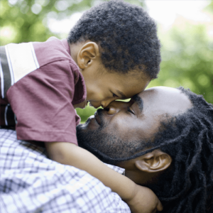 A father holding a son and smiling